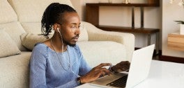 Image of man sitting on ground working on his laptop