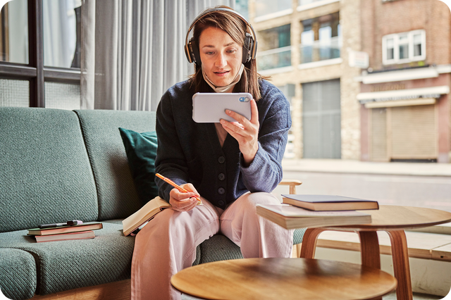Woman holding a phone while wearing headphones